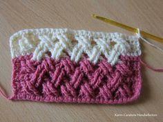 a pink and white crochet purse with a yellow knitting needle