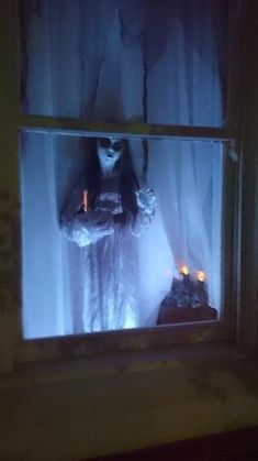 a creepy doll is standing in front of a window with candles on the windowsill