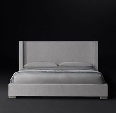 an upholstered bed with grey linens and silver sheets, in front of a black background