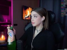 a woman sitting at a desk with a bottle of wine and headphones in front of her