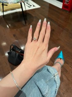 a woman's hand with white and silver nail polish on it, sitting on the floor