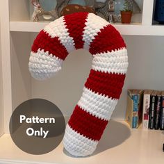 a knitted candy cane sitting on top of a book shelf