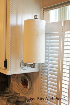 a toilet paper roll is hanging on the wall next to a window with shutters