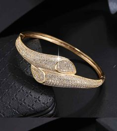 This stunning bracelet is crafted from 18K gold-plated copper for long-lasting shine. Its beautiful cubic zirconia design sparkles elegantly, making it a classy and timeless accessory for any ensemble. Formal Gold Bangle With Cubic Zirconia, Cubic Zirconia Gold Bangle Bracelet For Party, Party Gold Bangle Bracelet With Cubic Zirconia, Formal Gold Bangle Bracelet With Cubic Zirconia, Gold Cubic Zirconia Diamond Bracelet For Party, Elegant Gold Diamond Crystal Bracelet, Elegant Gold Crystal Bracelet With Diamonds, Dazzling Gold Cubic Zirconia Bracelet, Gold Crystal Bracelet With Cubic Zirconia