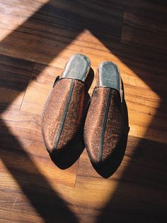 a pair of brown slippers sitting on top of a wooden floor