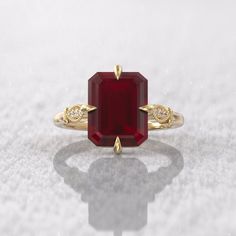 a red stone ring with two diamonds on it