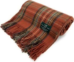 an orange and brown plaid blanket with a label on the front, sitting on a white surface