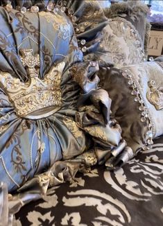 a pile of pillows sitting on top of a bed covered in blue and gold fabric