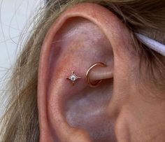 a woman's ear is shown with a tiny star and crescent piercing on it