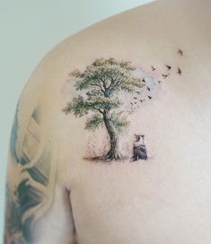 a man with a tree and dog tattoo on his shoulder