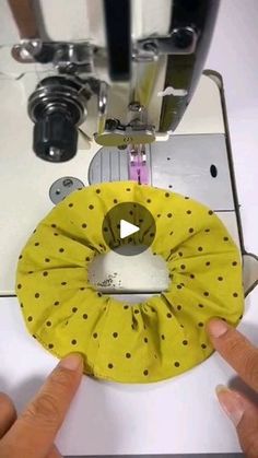 someone is using a sewing machine to sew something yellow and black with polka dots