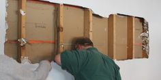 two men are working on the wall in an unfinished room