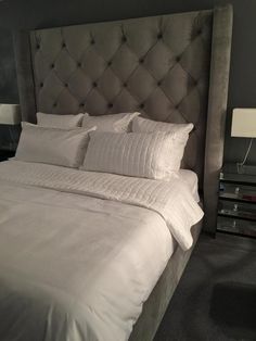 a bed with white sheets and pillows in a room