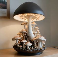 a lamp that is sitting on top of a table with mushrooms in the bottom half