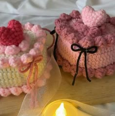 two crocheted cakes sitting on top of a table next to a lit candle