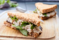 a cut in half sandwich sitting on top of a wooden cutting board