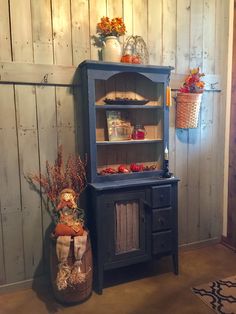 an old fashioned hutch in the corner of a room with baskets and flowers on it