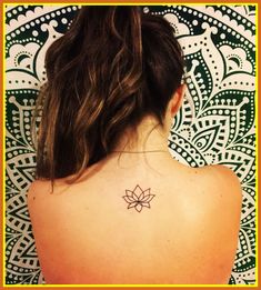 the back of a woman's neck with a lotus tattoo on her left shoulder