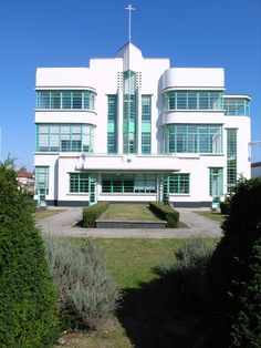 a large white building with lots of windows on it's sides and bushes in front of it