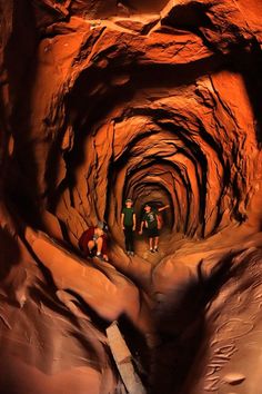 two people are standing in the middle of a dark tunnel that is filled with rocks