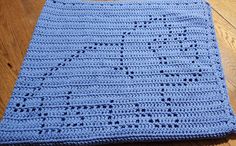 a blue crocheted blanket sitting on top of a wooden floor