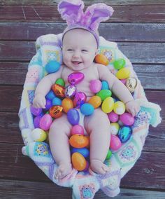 a baby is sitting in a basket filled with easter eggs