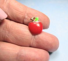 a person's hand holding a tiny red apple ring