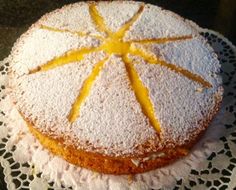 a cake with powdered sugar and lemon slices on top sits on a doily