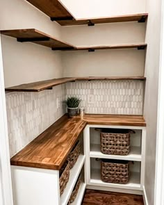 an empty pantry with wooden shelves and baskets