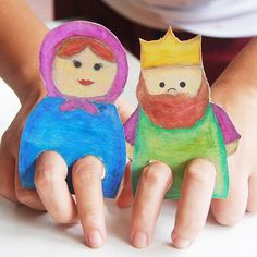 two children's hands holding small paper dolls