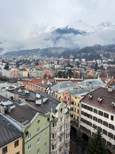 the city is surrounded by tall buildings and mountains in the distance with snow on top