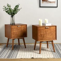 two wooden nightstands with candles on them in front of a white wall and rug