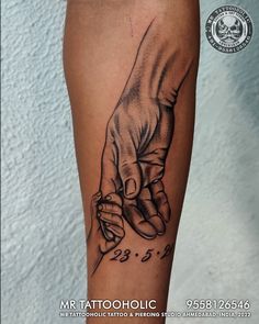 a black and white tattoo on the leg of a person holding hands with numbers in it