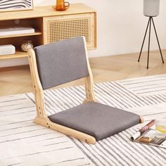 a gray chair sitting on top of a white rug next to a wooden table and shelf