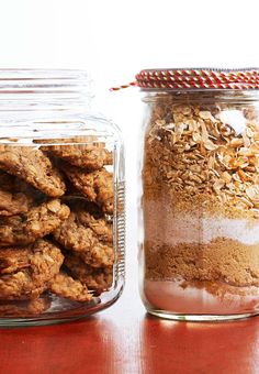 two glass jars filled with cookies on top of a wooden table