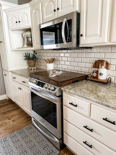 a kitchen with white cabinets and granite counter tops, stainless steel appliances and an oven