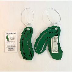 two green alligator shaped key chains with money attached to them