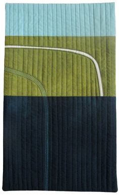 a quilted blanket with blue and green stripes on it's sides, along with a white strip in the center