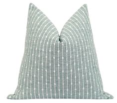 a light blue and white pillow with dots on it, sitting on a white background