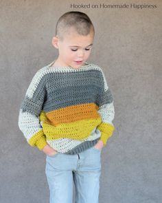 a young boy wearing a multicolored sweater