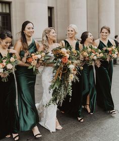 a group of women standing next to each other in front of a building holding bouquets