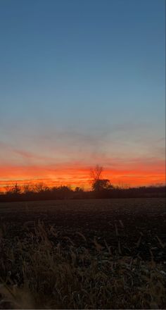 the sun is setting over an empty field