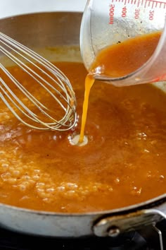 a whisk being poured into a pan filled with sauce