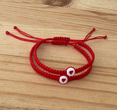 The Red String of Fate is a story of destiny that explains how people are meant to be together. They are linked by a red string attached to their hands until they find each other. It is also believed that the red string helps to channel positive energy for good luck and provide protection against evil. Bracelet Features: (1) 1mm Durable Nylon Cord (2) Bracelet is adjustable to fit most wrist sizes (3) Bracelet thickness (width) is 5mm (4) 7mm Acrylic Heart Bead Matching Bracelets String, Matching Beaded Bracelets For Couples, Red Braided Bracelets For Valentine's Day, Matching String Bracelets, Couple Bracelets Diy, Couple Beaded Bracelets, Cute Matching Bracelets, Nylon String Bracelet, Matching Heart Bracelet