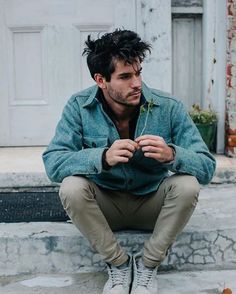 a man is sitting on the steps with his hands in his pockets and looking down