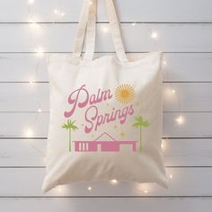 a tote bag with palm springs on it hanging from a string of christmas lights