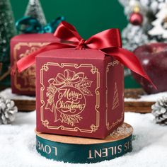 a red christmas gift box sitting on top of snow covered ground