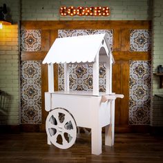 a small white cart with wheels in front of a brick wall