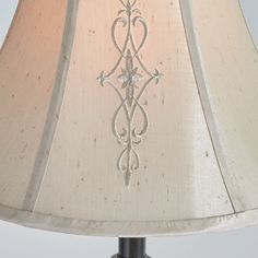 a lamp that is on top of a table with a light shade over it and an ornate design