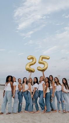 a group of young women standing next to each other on top of a sandy beach